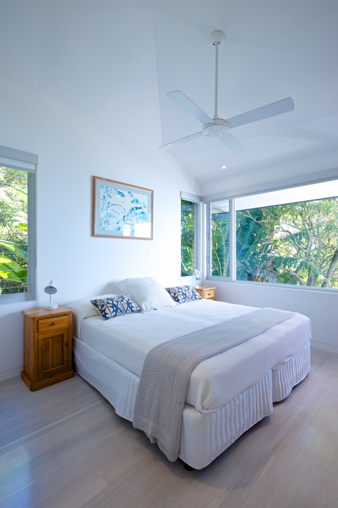 Inspiration for a mid-sized beach style guest bedroom in Sydney with white walls, light hardwood floors and beige floor.