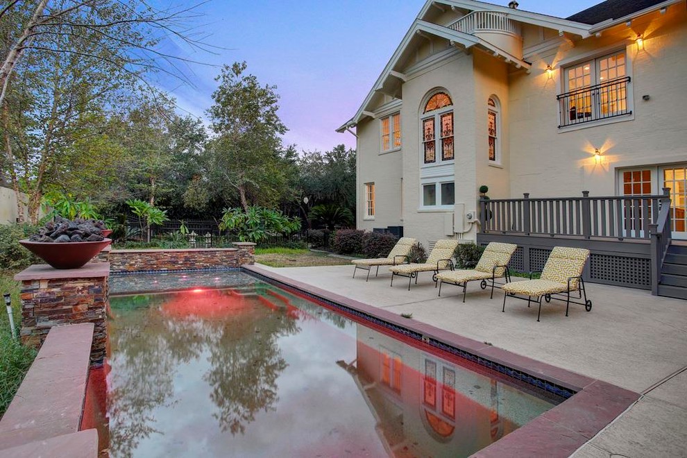 This is an example of a large traditional backyard deck in Houston with a water feature and a roof extension.