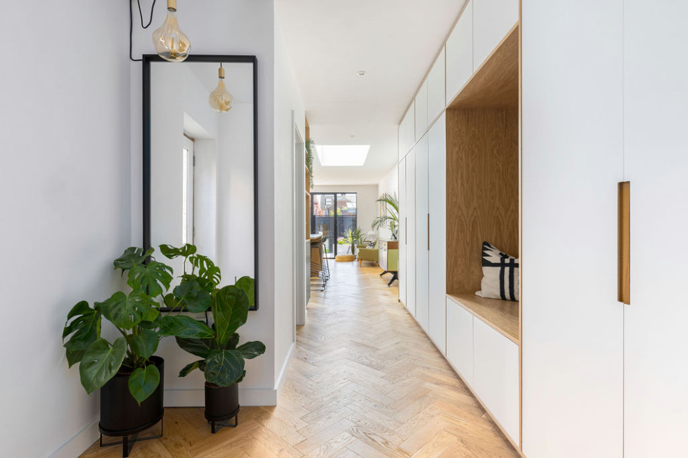 Immagine di un'ampia sala da pranzo aperta verso la cucina minimalista con pareti bianche, pavimento in legno massello medio e pavimento beige