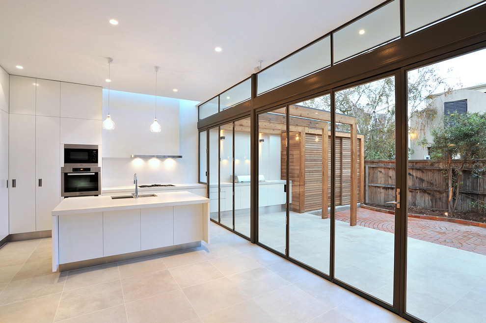 Design ideas for a mid-sized contemporary l-shaped kitchen pantry in Melbourne with an undermount sink, flat-panel cabinets, white cabinets, quartz benchtops, white splashback, glass sheet splashback, stainless steel appliances, ceramic floors and with island.