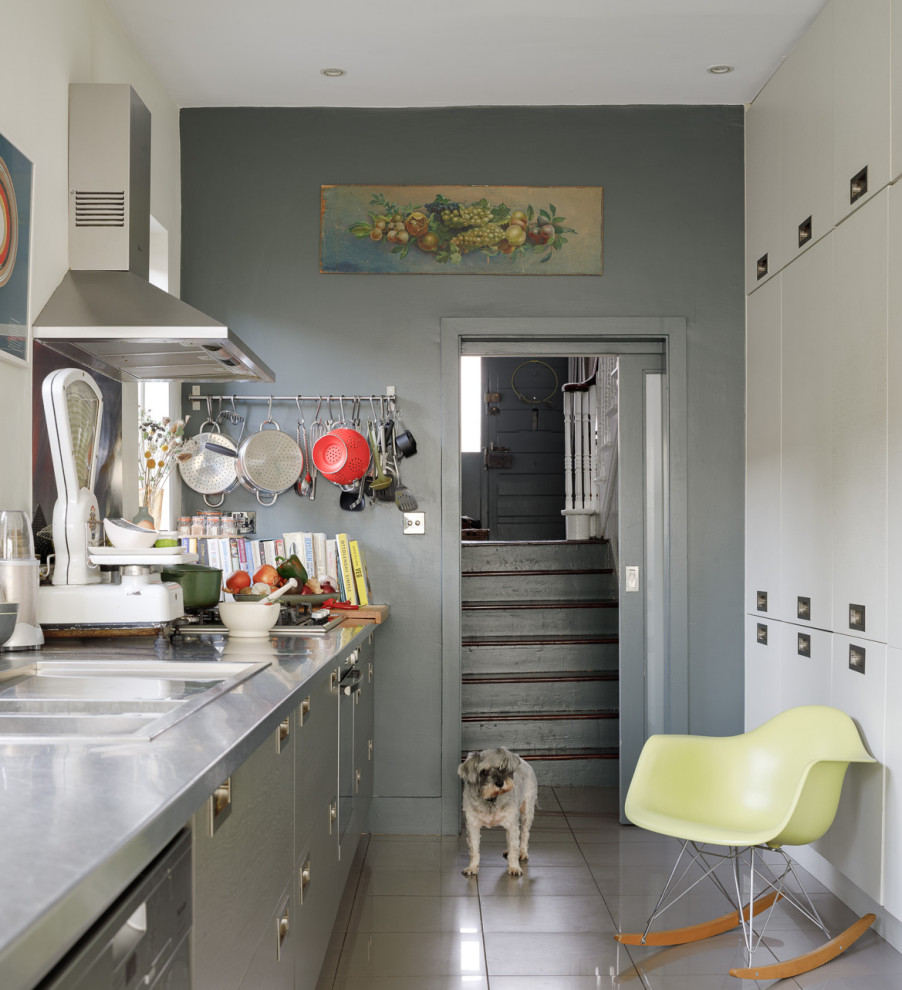 Photo of an eclectic galley separate kitchen in Dublin with a drop-in sink, flat-panel cabinets, grey cabinets, stainless steel benchtops, stainless steel appliances, no island, grey floor and grey benchtop.