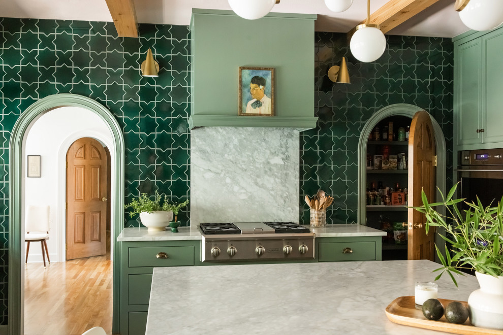 Eklektisk inredning av ett stort vit vitt kök, med gröna skåp, grönt stänkskydd, stänkskydd i keramik, rostfria vitvaror, ljust trägolv och en köksö