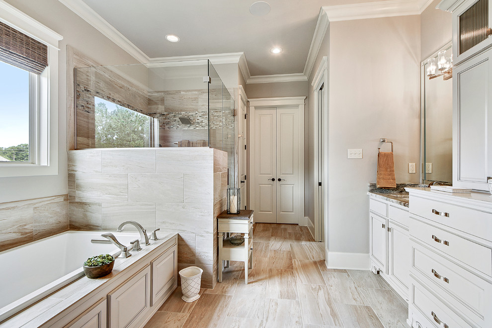 Inspiration for a mid-sized transitional master bathroom in New Orleans with beaded inset cabinets, white cabinets, a drop-in tub, a corner shower, gray tile, stone tile, grey walls, porcelain floors, an undermount sink, marble benchtops, beige floor, a hinged shower door and grey benchtops.