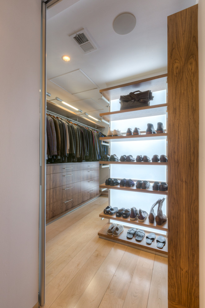 This is an example of an expansive modern gender-neutral walk-in wardrobe in Kansas City with flat-panel cabinets, medium wood cabinets and light hardwood floors.