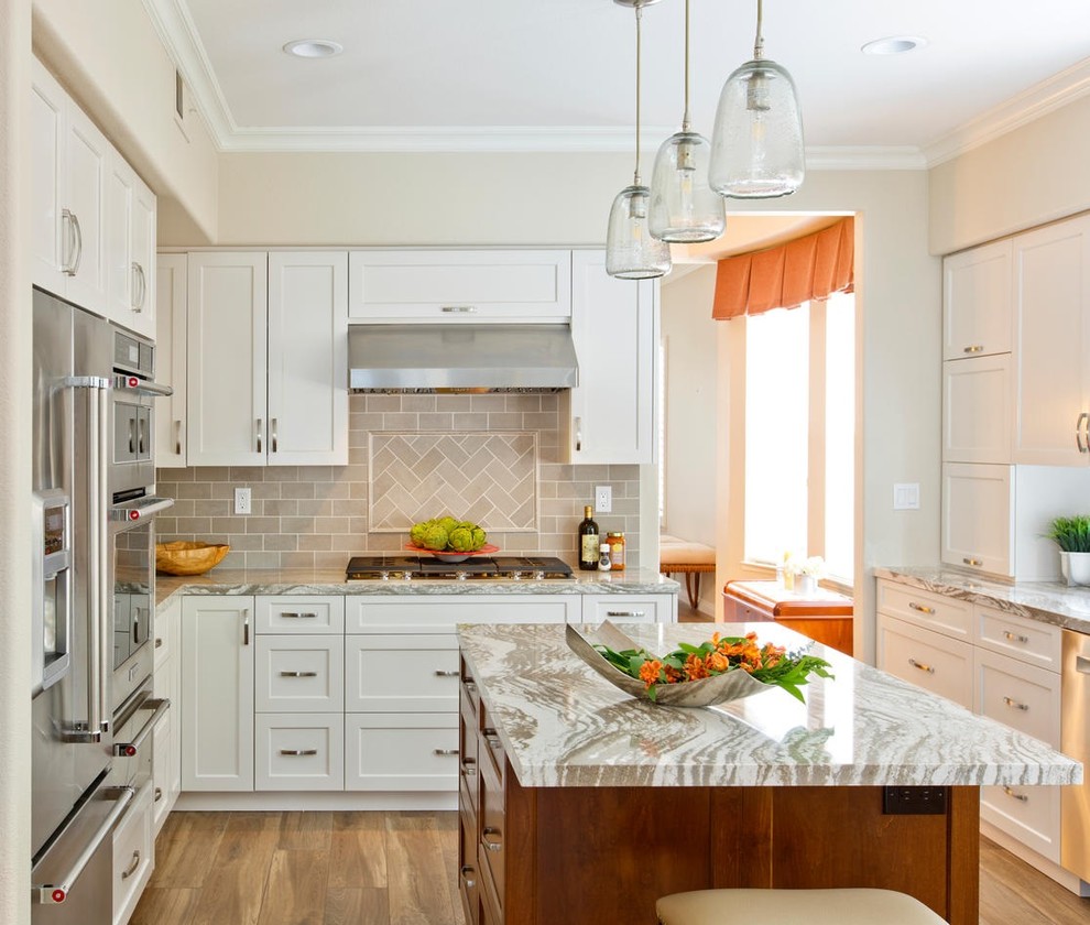 Transitional u-shaped separate kitchen in San Diego with recessed-panel cabinets, white cabinets, grey splashback, stainless steel appliances, medium hardwood floors, with island and brown floor.
