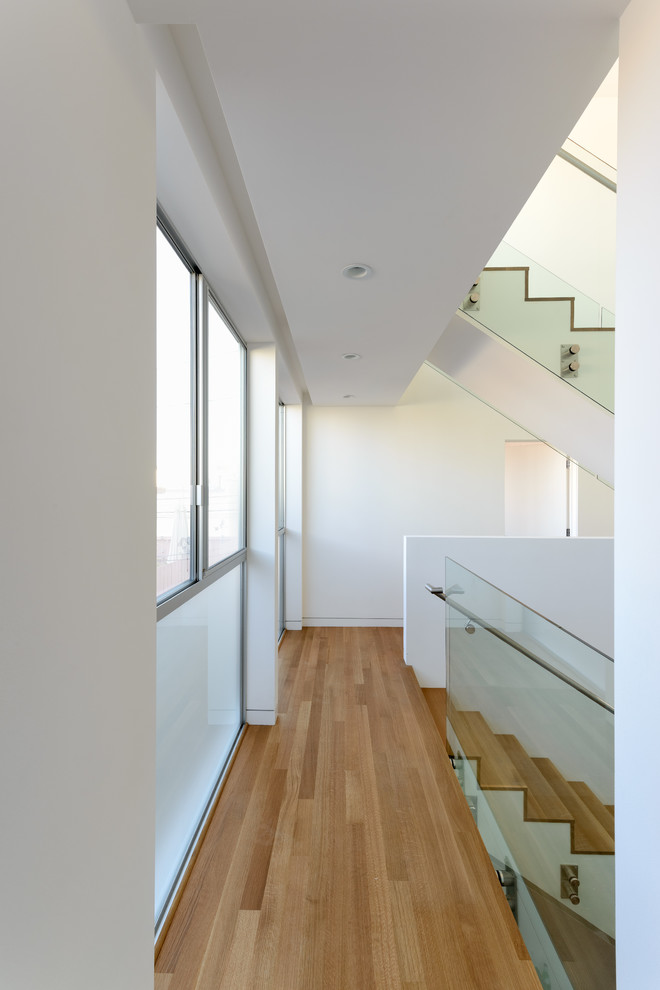 Photo of a contemporary wood staircase in Los Angeles with wood risers and glass railing.