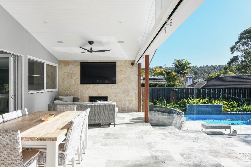 Foto di un ampio patio o portico moderno dietro casa con un focolare, un caminetto, pavimentazioni in cemento e un tetto a sbalzo