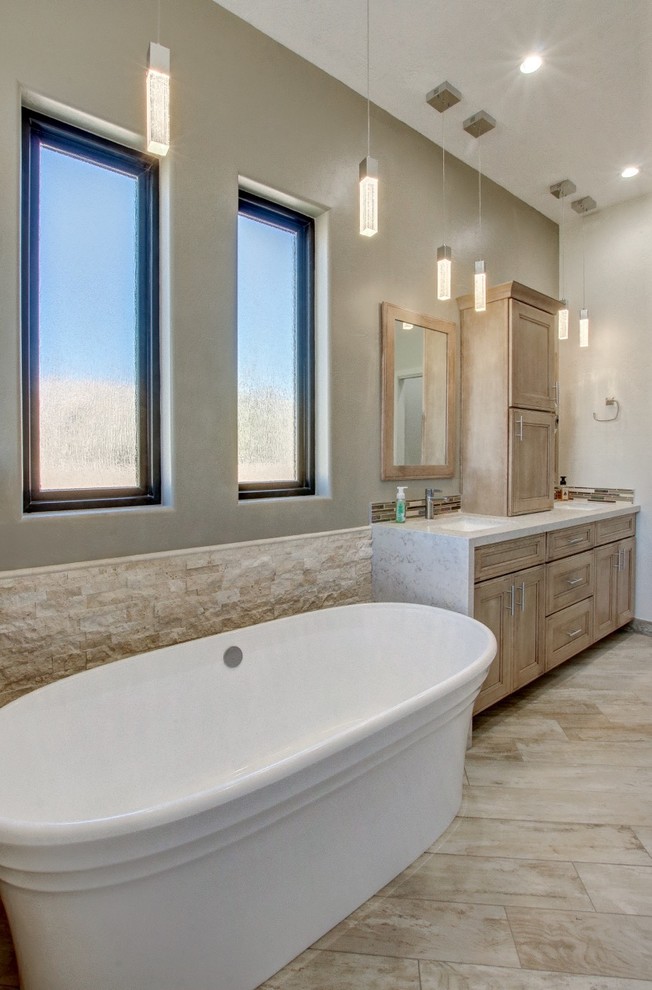 Inspiration for a mid-sized contemporary master bathroom in Phoenix with recessed-panel cabinets, light wood cabinets, a freestanding tub, a curbless shower, a one-piece toilet, beige tile, stone tile, beige walls, porcelain floors, an undermount sink, engineered quartz benchtops, beige floor, an open shower and white benchtops.