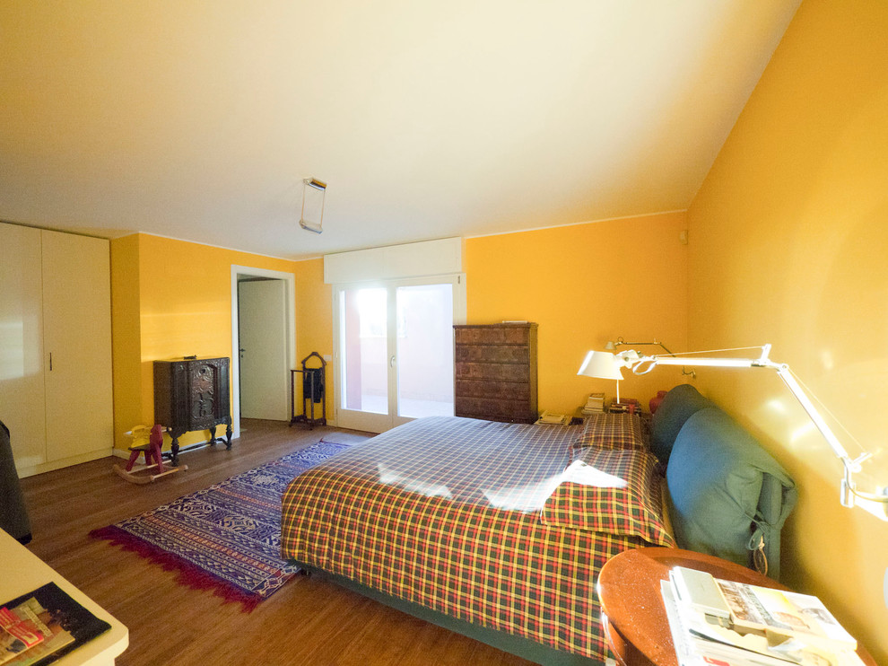 Photo of a large eclectic master bedroom in Milan with yellow walls and bamboo floors.