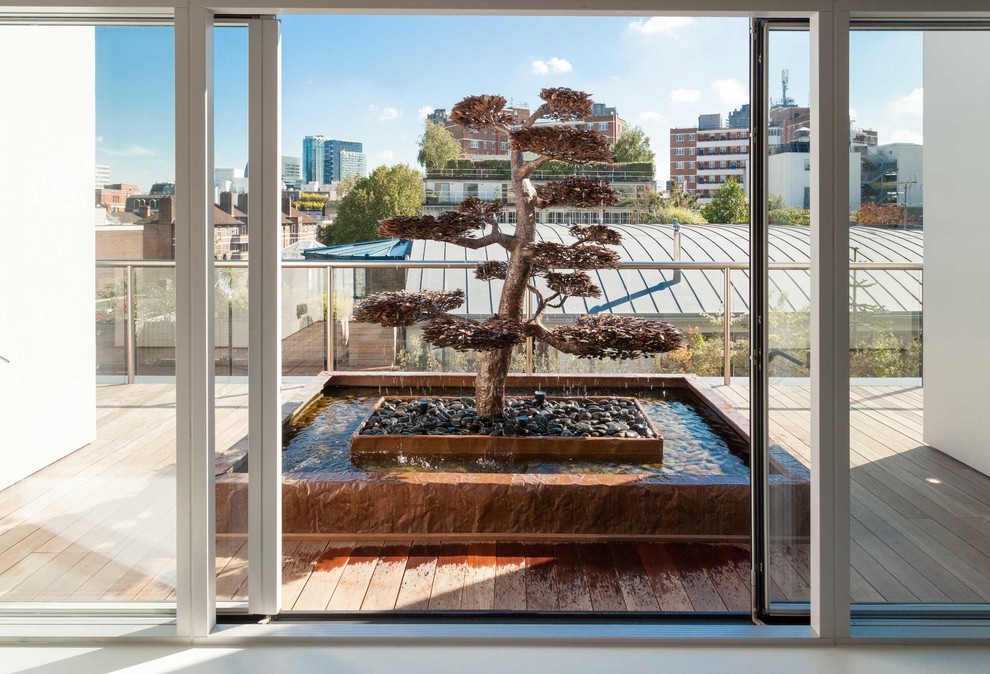 Inspiration for a large contemporary rooftop deck in London with a water feature and a pergola.