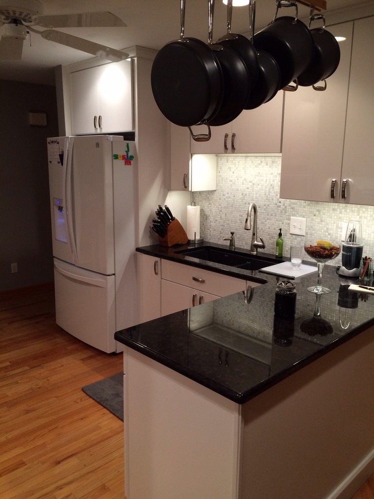 Example of a mid-sized l-shaped light wood floor eat-in kitchen design with an undermount sink, white cabinets, granite countertops, gray backsplash, mosaic tile backsplash and white appliances