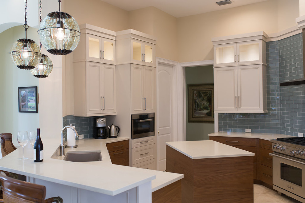 Enclosed kitchen - large transitional u-shaped porcelain tile and beige floor enclosed kitchen idea in Miami with an undermount sink, beaded inset cabinets, white cabinets, quartzite countertops, blue backsplash, subway tile backsplash, stainless steel appliances and an island