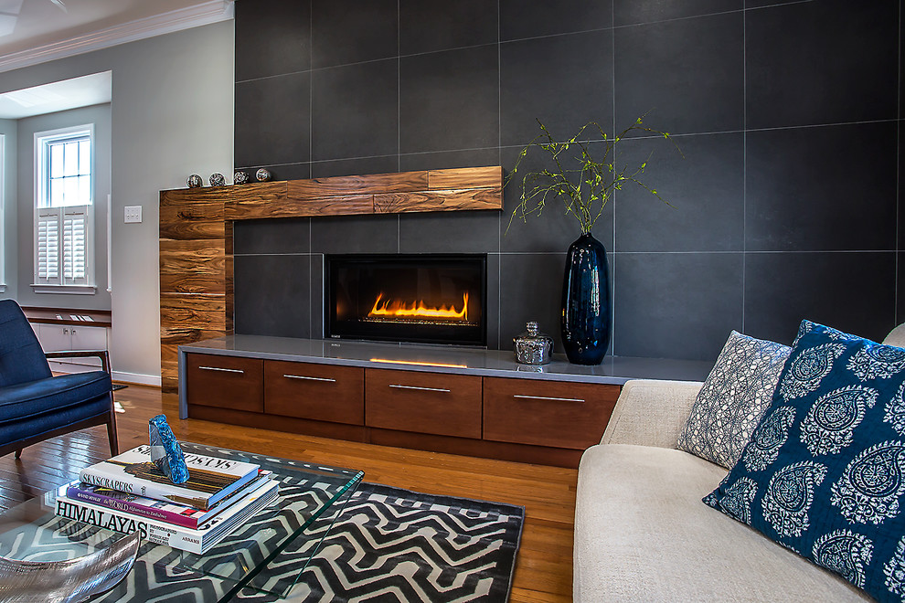 This is an example of a mid-sized midcentury open concept family room in Richmond with grey walls, medium hardwood floors, a standard fireplace, a tile fireplace surround and brown floor.