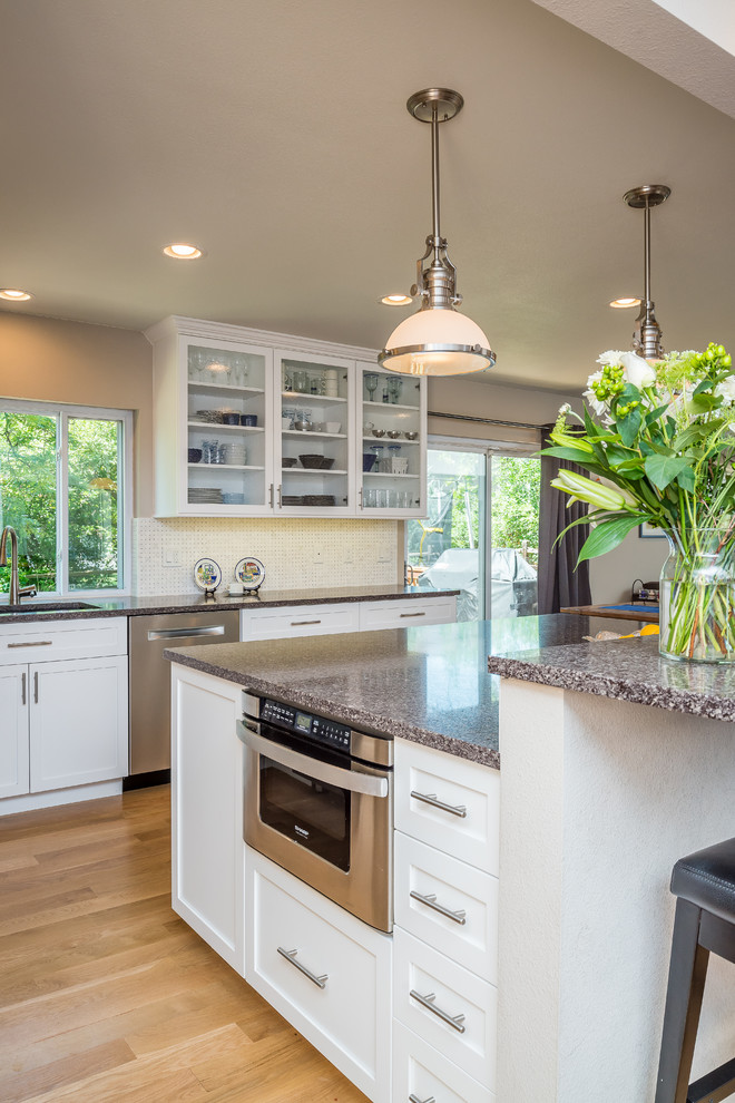 Example of a mid-sized transitional l-shaped eat-in kitchen design in Denver with shaker cabinets, white cabinets, quartz countertops, white backsplash, colored appliances and an island