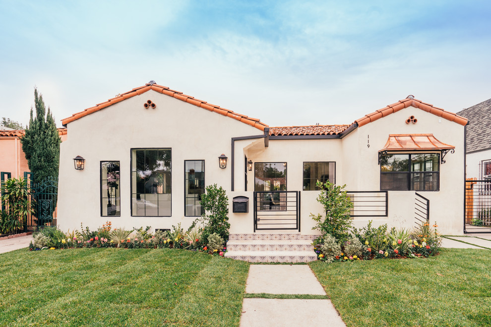 Mediterranean one-storey white house exterior in Los Angeles with stone veneer, a gable roof and a tile roof.