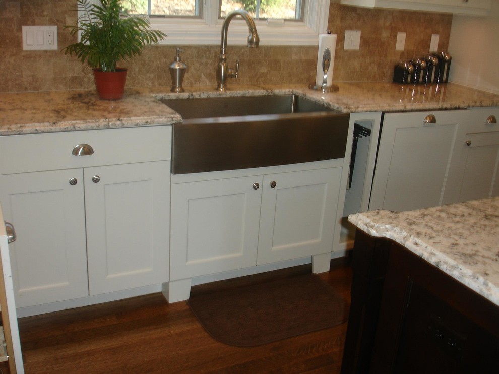 Example of a transitional l-shaped dark wood floor eat-in kitchen design in New York with a double-bowl sink, raised-panel cabinets, white cabinets, granite countertops, beige backsplash, stone tile backsplash, stainless steel appliances and an island