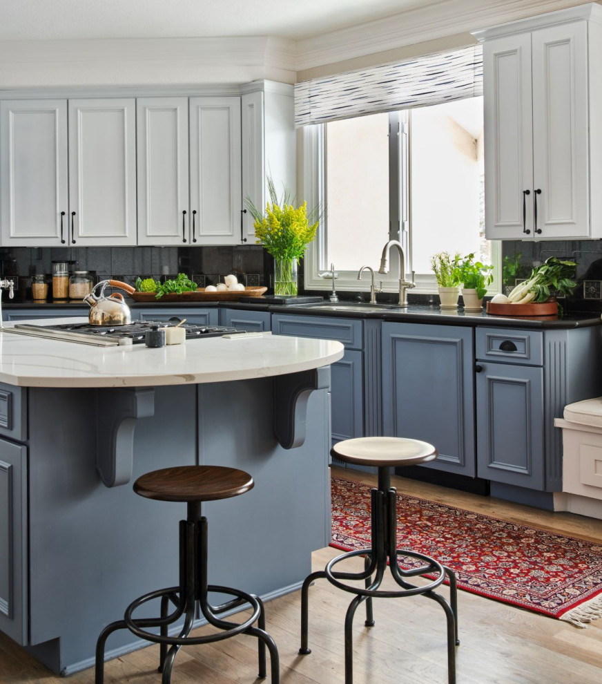 Inspiration for a mid-sized transitional u-shaped eat-in kitchen in Denver with an undermount sink, beaded inset cabinets, blue cabinets, quartz benchtops, black splashback, granite splashback, panelled appliances, medium hardwood floors, with island, brown floor, white benchtop and recessed.