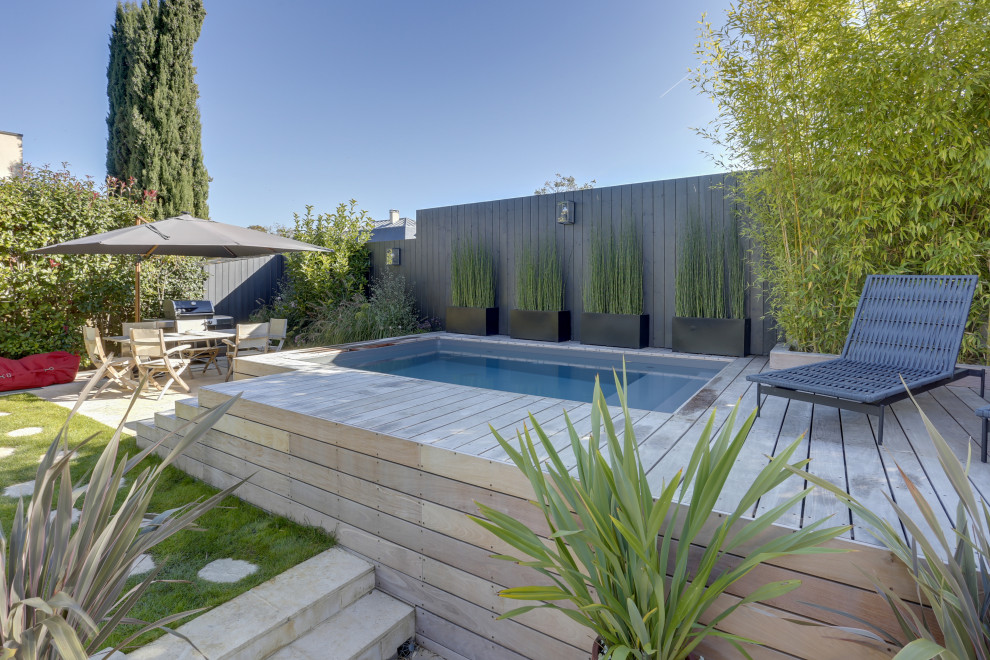 Imagen de piscina elevada contemporánea pequeña rectangular en patio delantero con paisajismo de piscina y entablado