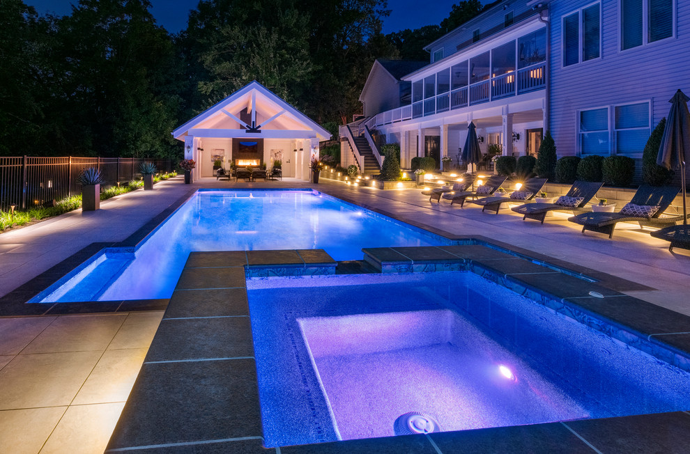 Large transitional backyard rectangular lap pool in Other with a pool house and concrete pavers.