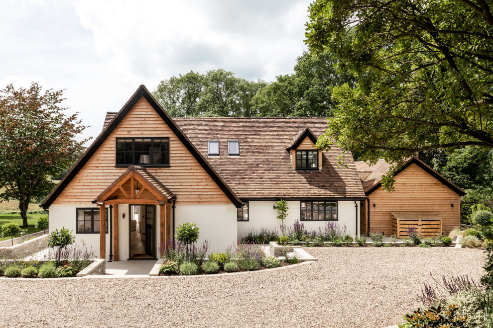 Design ideas for a large farmhouse two floor front extension in Sussex with wood cladding, a pitched roof, a tiled roof, a red roof and board and batten cladding.