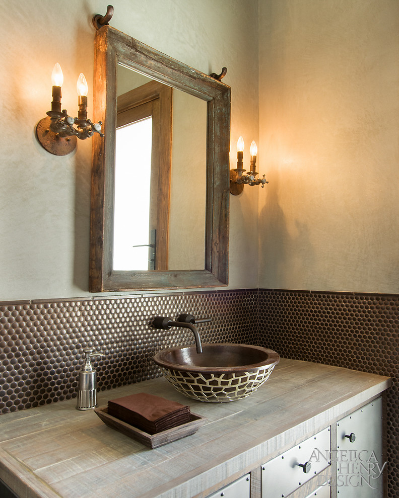Photo of a country powder room in Phoenix with a vessel sink, wood benchtops, a one-piece toilet, brown tile, metal tile and green walls.