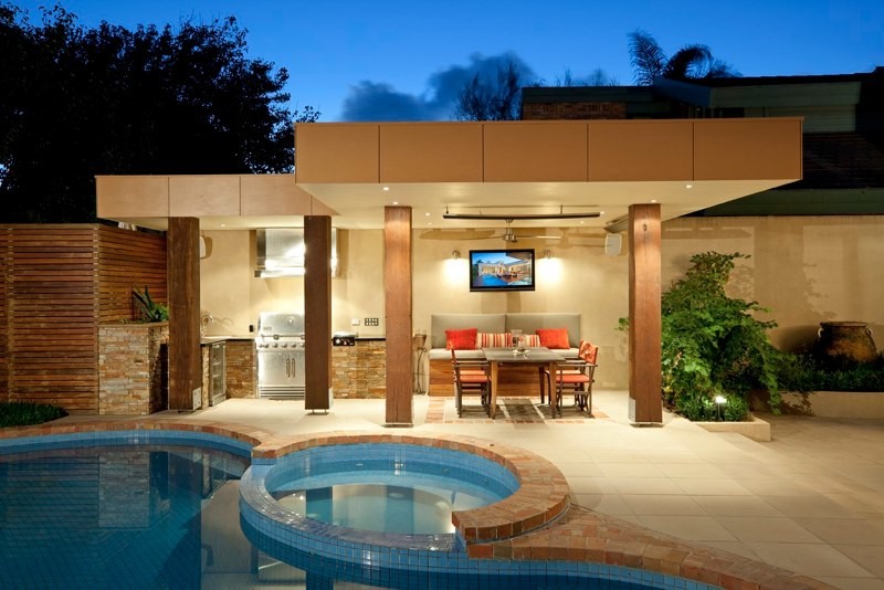 Photo of a mid-sized contemporary backyard custom-shaped lap pool in Melbourne with mixed siding, a flat roof, a hot tub and stamped concrete.