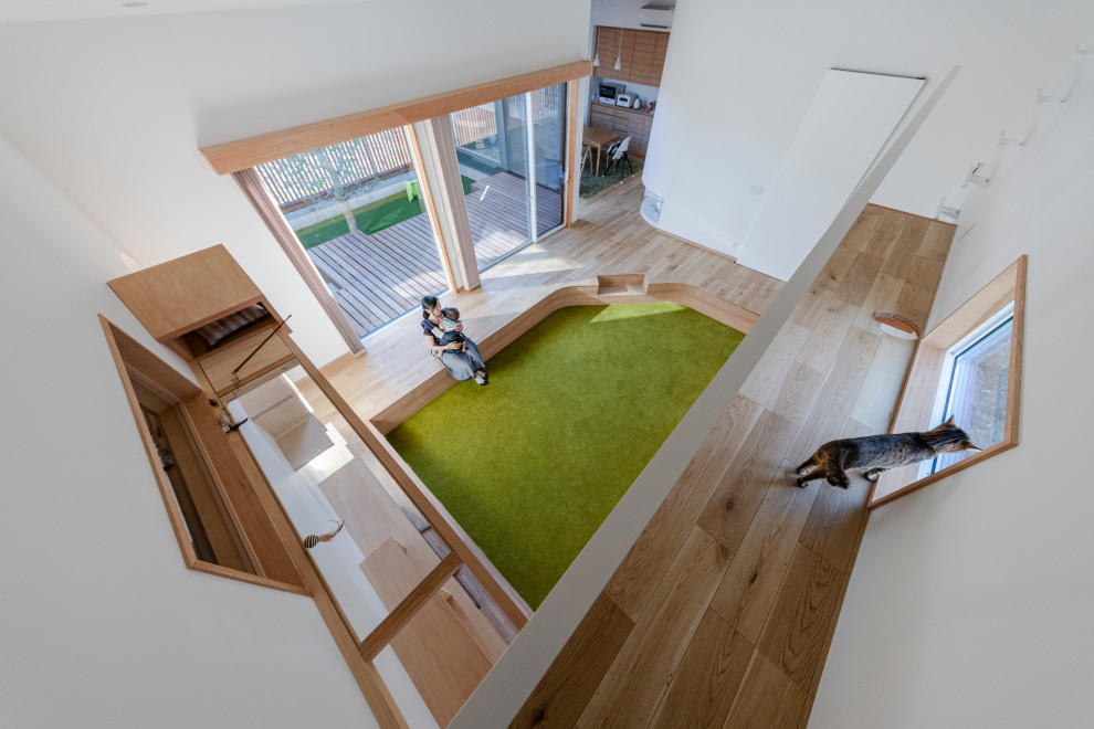 На фото: открытая гостиная комната среднего размера в скандинавском стиле с белыми стенами, ковровым покрытием, телевизором на стене, зеленым полом, потолком с обоями и обоями на стенах с