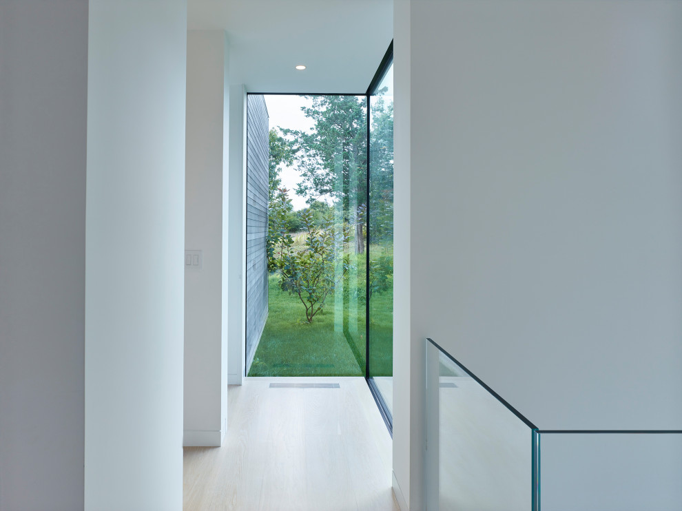 This is an example of a mid-sized contemporary hallway in Other with white walls, light hardwood floors and beige floor.