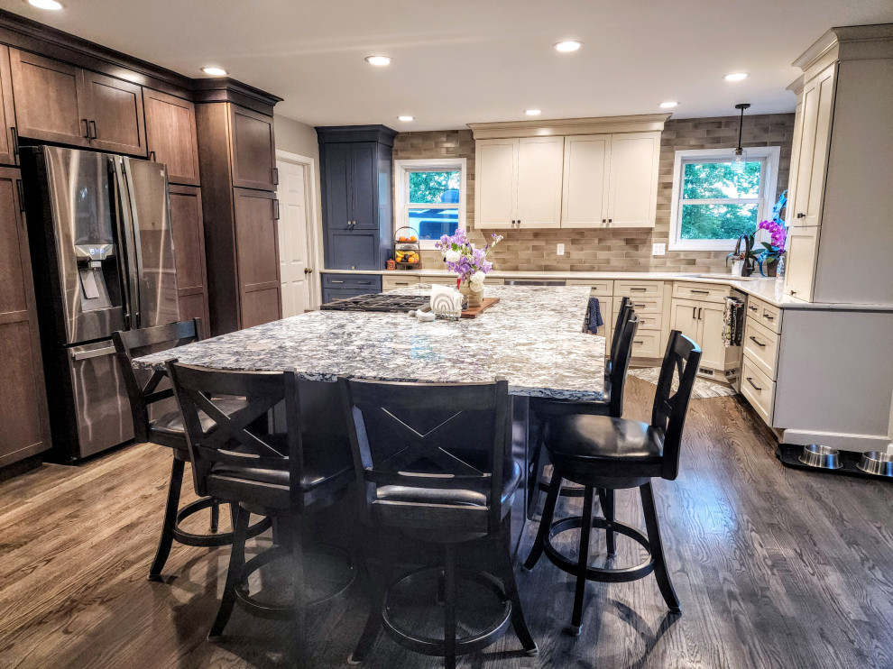 Large country l-shaped medium tone wood floor and gray floor eat-in kitchen photo with an undermount sink, shaker cabinets, subway tile backsplash, stainless steel appliances, an island and multicolored countertops