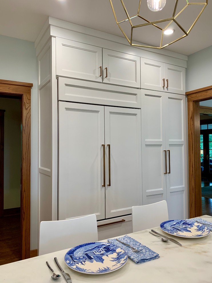 Design ideas for a mid-sized traditional u-shaped open plan kitchen in Milwaukee with a farmhouse sink, recessed-panel cabinets, blue cabinets, marble benchtops, multi-coloured splashback, terra-cotta splashback, panelled appliances, medium hardwood floors, with island and white benchtop.