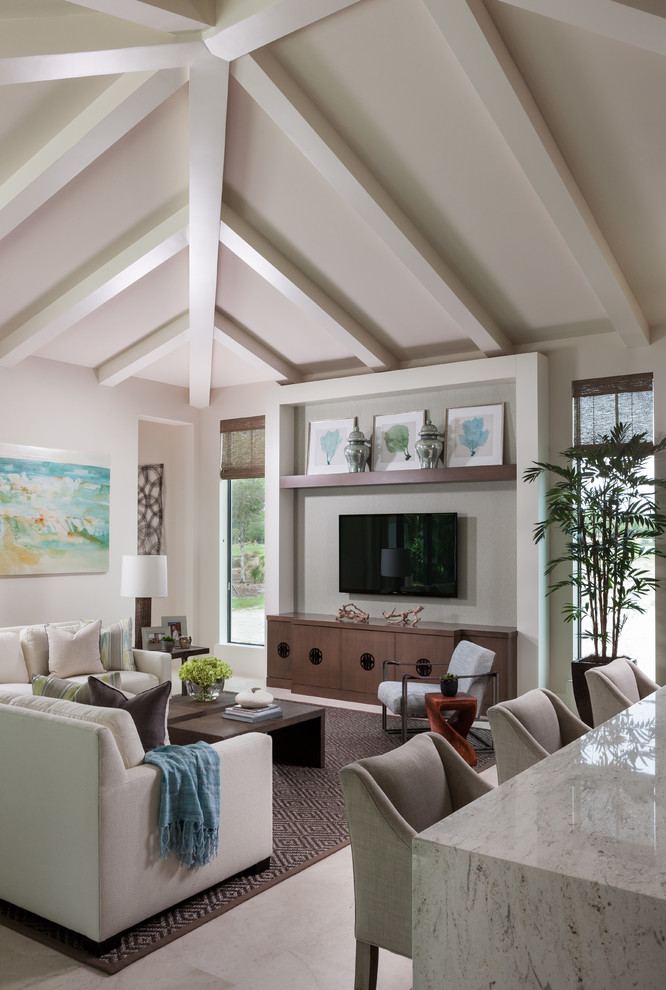 This is an example of a transitional family room in Miami with white walls, a wall-mounted tv and beige floor.
