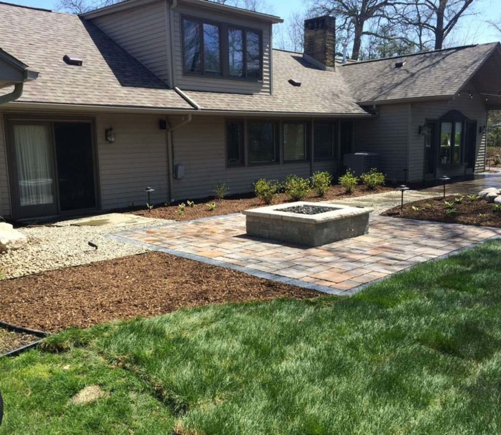 Photo of a mid-sized traditional partial sun backyard stone landscaping in Detroit with a fire pit.