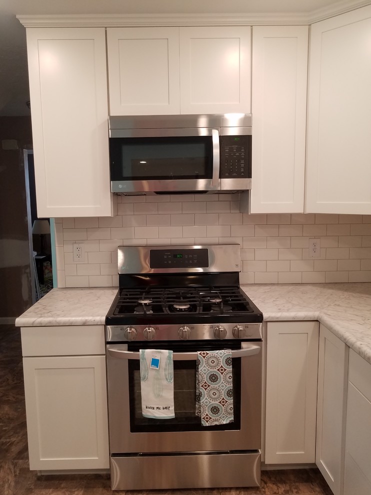 Inspiration for a mid-sized transitional l-shaped vinyl floor and beige floor eat-in kitchen remodel in Cincinnati with a single-bowl sink, shaker cabinets, white cabinets, laminate countertops, white backsplash, porcelain backsplash, stainless steel appliances and no island