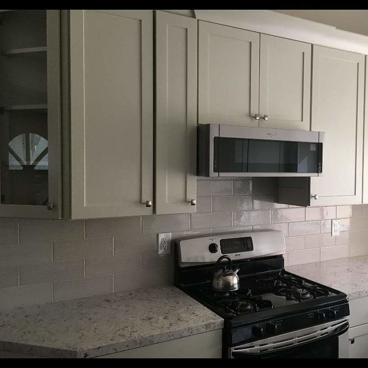 Large transitional u-shaped dark wood floor and brown floor eat-in kitchen photo in Los Angeles with an undermount sink, recessed-panel cabinets, gray cabinets, quartzite countertops, white backsplash, ceramic backsplash, stainless steel appliances, an island and white countertops