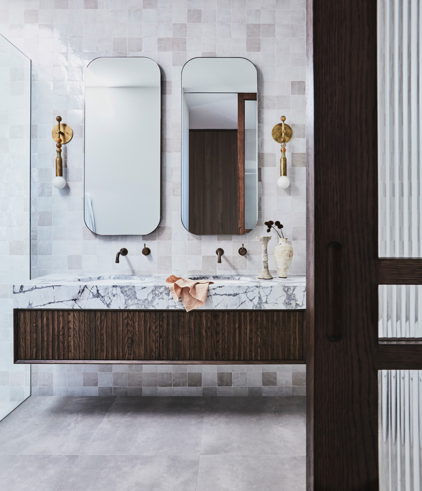 Photo of a large contemporary master bathroom in Sydney with louvered cabinets, brown cabinets, a freestanding tub, an open shower, beige tile, porcelain tile, white walls, ceramic floors, an integrated sink, marble benchtops, multi-coloured floor, an open shower, grey benchtops, a double vanity and a floating vanity.