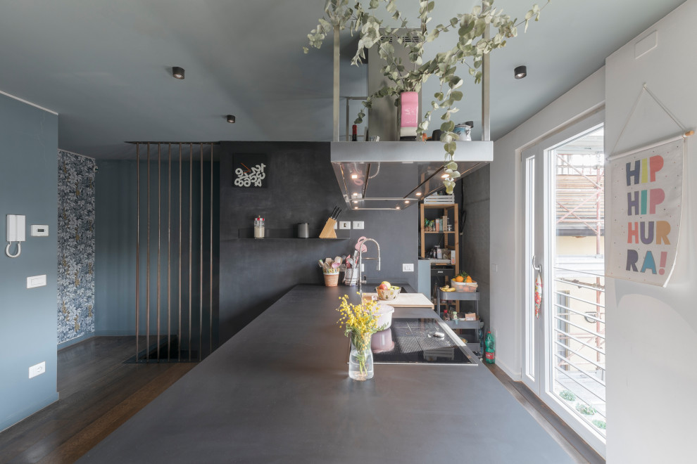 Photo of a large contemporary single-wall open plan kitchen in Milan with an integrated sink, flat-panel cabinets, black cabinets, composite countertops, black splashback, dark hardwood flooring, a breakfast bar, grey floors and black worktops.