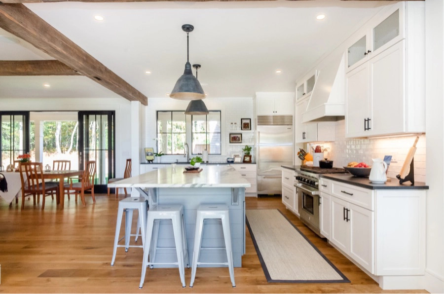 Foto di una cucina stile marinaro con paraspruzzi bianco, elettrodomestici in acciaio inossidabile, pavimento in legno massello medio, pavimento marrone e travi a vista