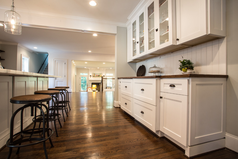 Example of a transitional dark wood floor open concept kitchen design in Atlanta with a farmhouse sink, shaker cabinets, white cabinets, marble countertops, white backsplash, subway tile backsplash, stainless steel appliances and an island