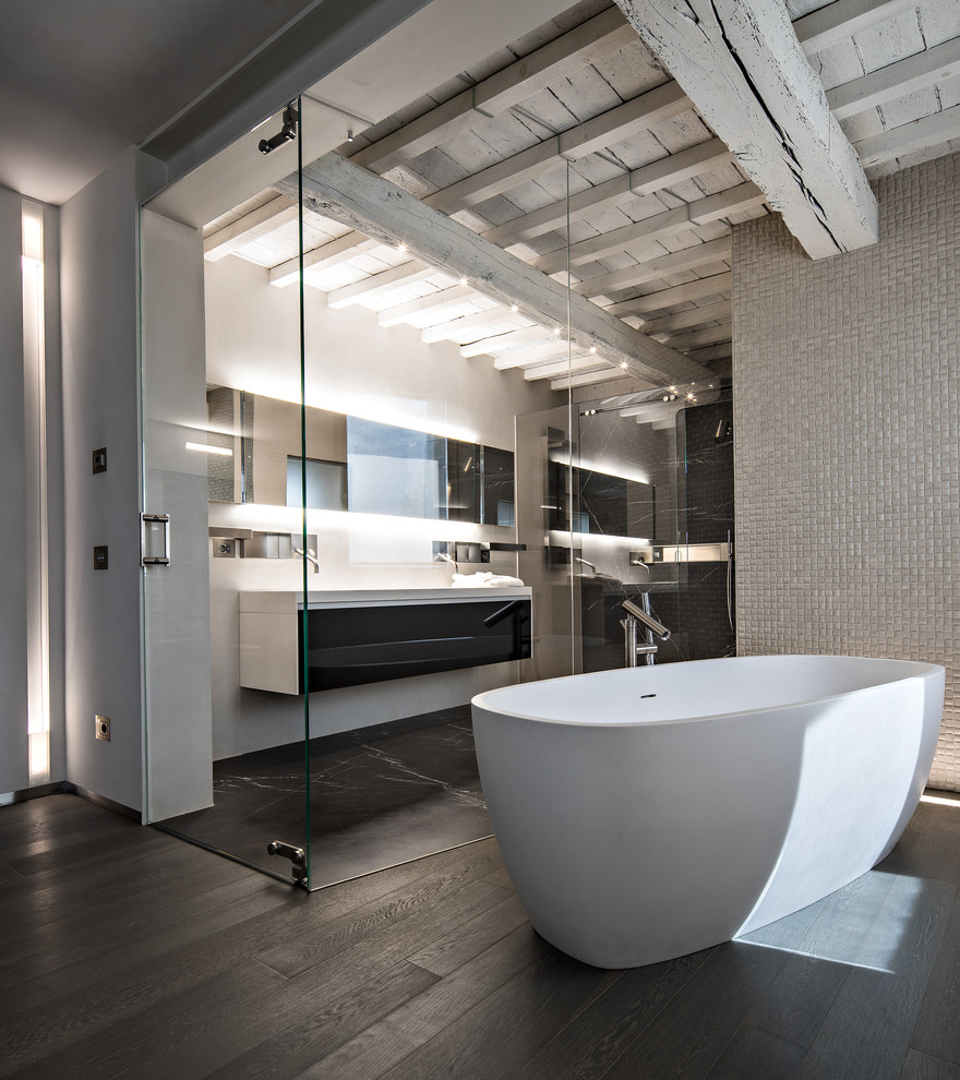 Photo of a large contemporary master bathroom in Bologna with flat-panel cabinets, black cabinets, a freestanding tub, grey walls, gray tile and dark hardwood floors.