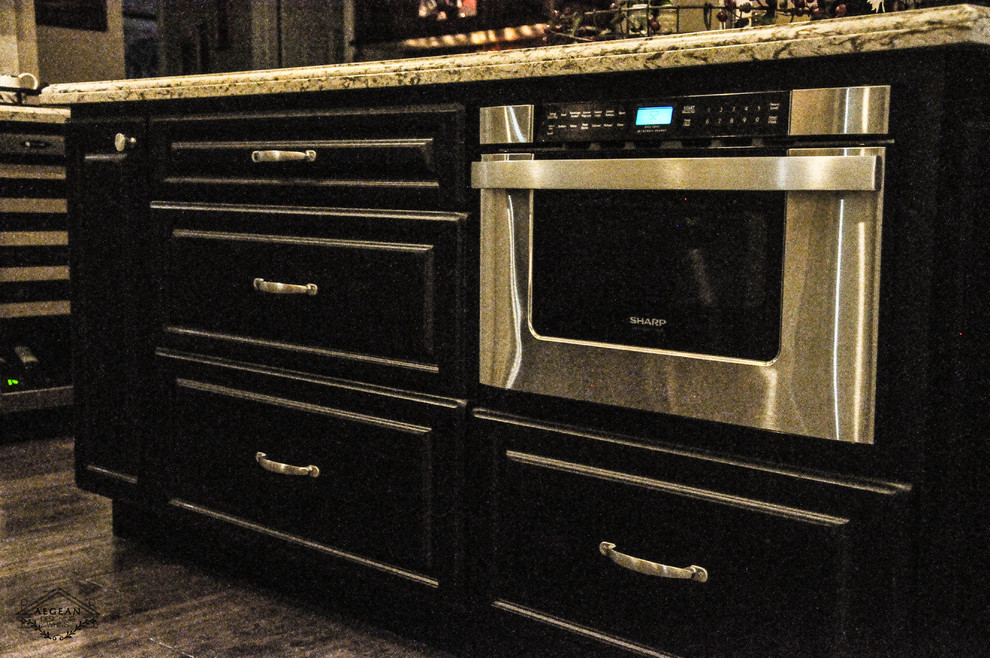 Inspiration for a mid-sized transitional u-shaped eat-in kitchen remodel in Los Angeles with raised-panel cabinets, black cabinets, granite countertops, beige backsplash, ceramic backsplash, stainless steel appliances, an island and a single-bowl sink