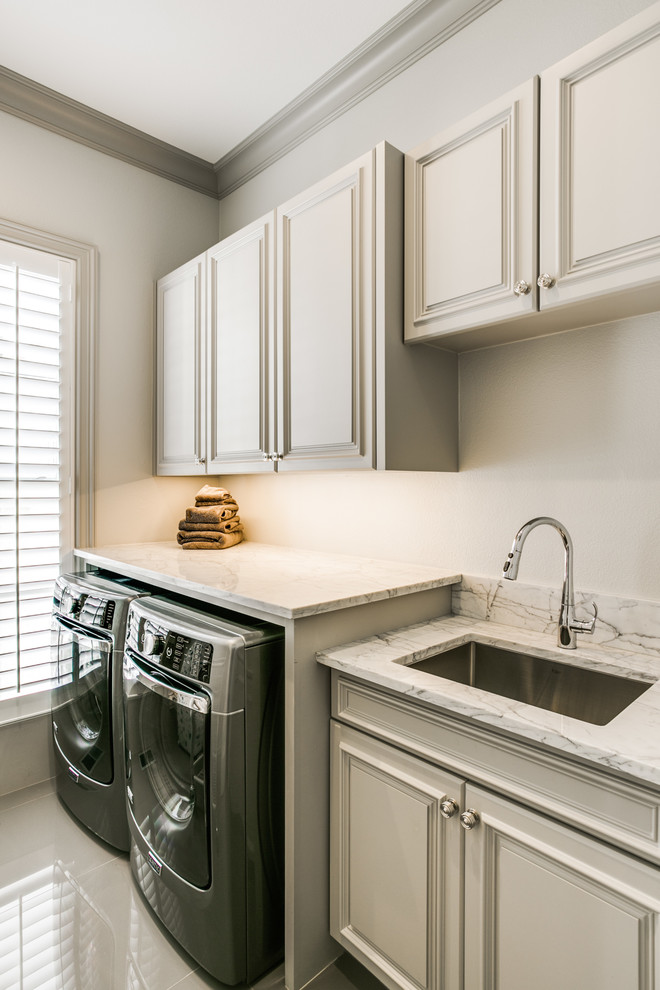 Design ideas for a large traditional single-wall utility room in Dallas with an undermount sink, white cabinets, marble benchtops, white walls, a side-by-side washer and dryer, raised-panel cabinets and marble floors.