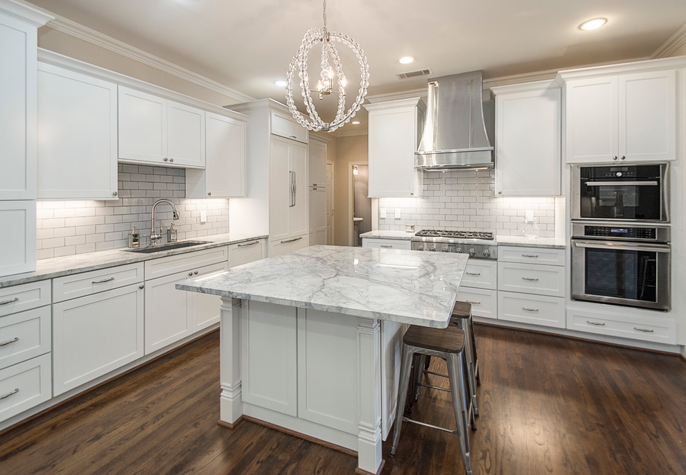 Example of a large transitional u-shaped medium tone wood floor open concept kitchen design in Dallas with an undermount sink, shaker cabinets, white cabinets, quartz countertops, white backsplash, porcelain backsplash, stainless steel appliances and an island