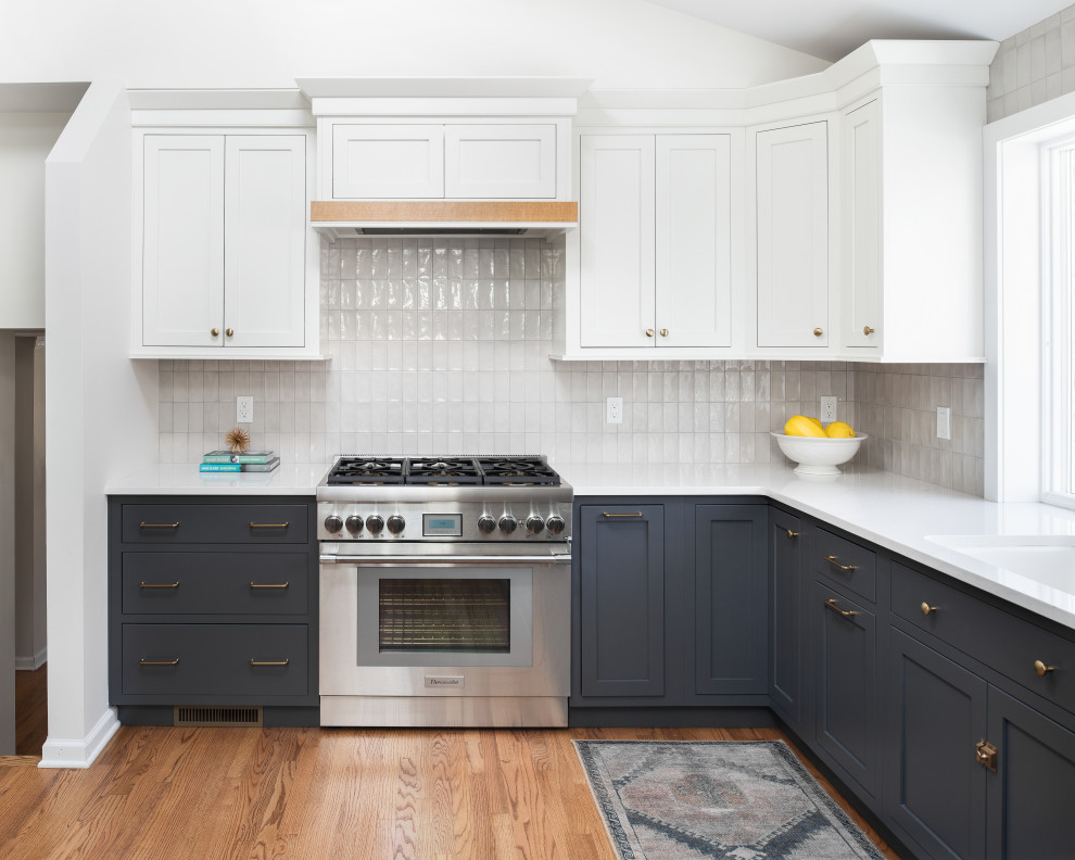 Foto på ett mellanstort vintage vit kök, med en undermonterad diskho, luckor med profilerade fronter, grå skåp, bänkskiva i kvarts, grått stänkskydd, stänkskydd i porslinskakel, rostfria vitvaror och mellanmörkt trägolv