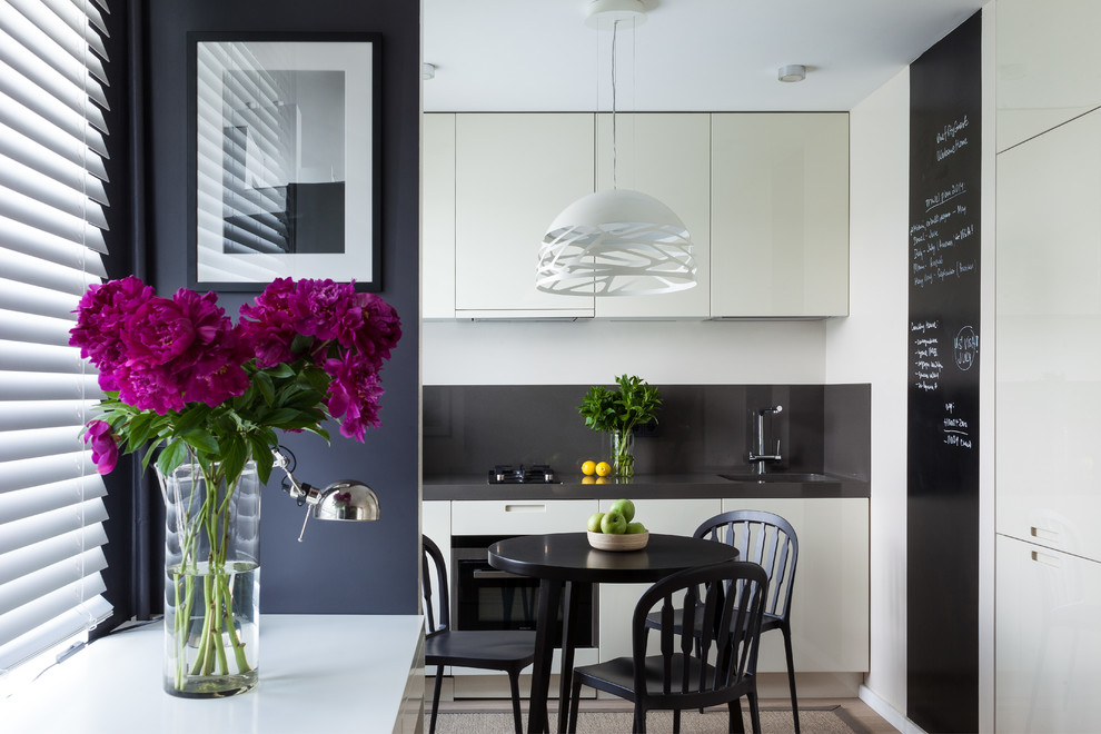 Contemporary single-wall eat-in kitchen in Moscow with an undermount sink, flat-panel cabinets, black splashback and stainless steel appliances.