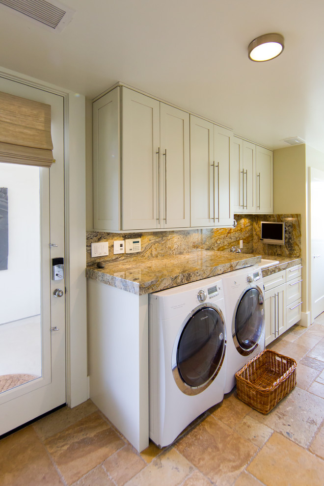 Large traditional galley dedicated laundry room in San Luis Obispo with a single-bowl sink, raised-panel cabinets, white cabinets, granite benchtops, white walls, travertine floors and a side-by-side washer and dryer.