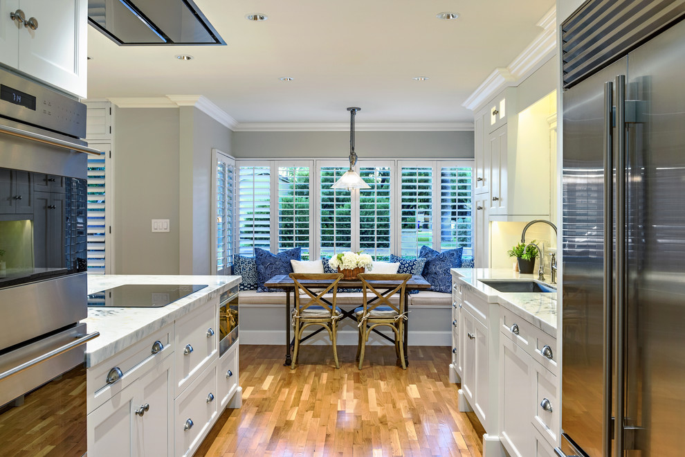 Example of a mid-sized transitional single-wall medium tone wood floor enclosed kitchen design in Phoenix with an undermount sink, shaker cabinets, white cabinets, marble countertops, gray backsplash, subway tile backsplash, stainless steel appliances and an island