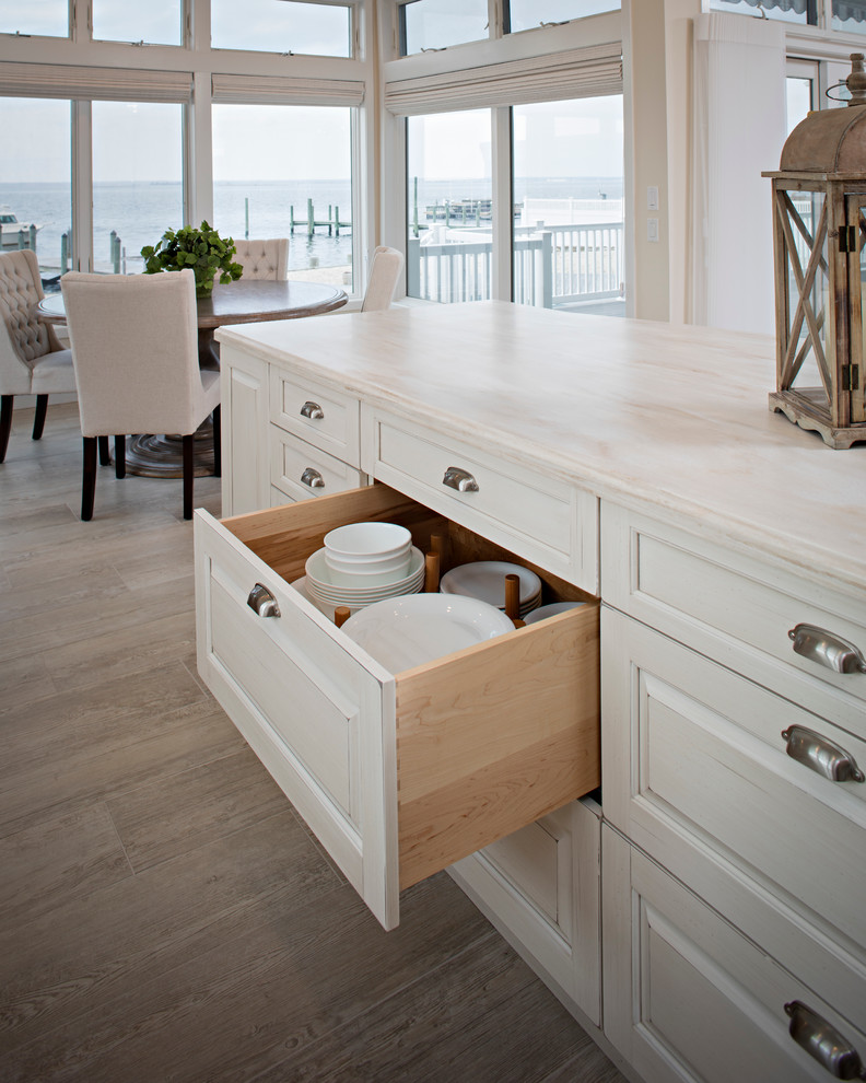 Example of a mid-sized beach style galley porcelain tile open concept kitchen design with solid surface countertops, an island, an undermount sink, raised-panel cabinets, white cabinets, multicolored backsplash, mosaic tile backsplash and stainless steel appliances