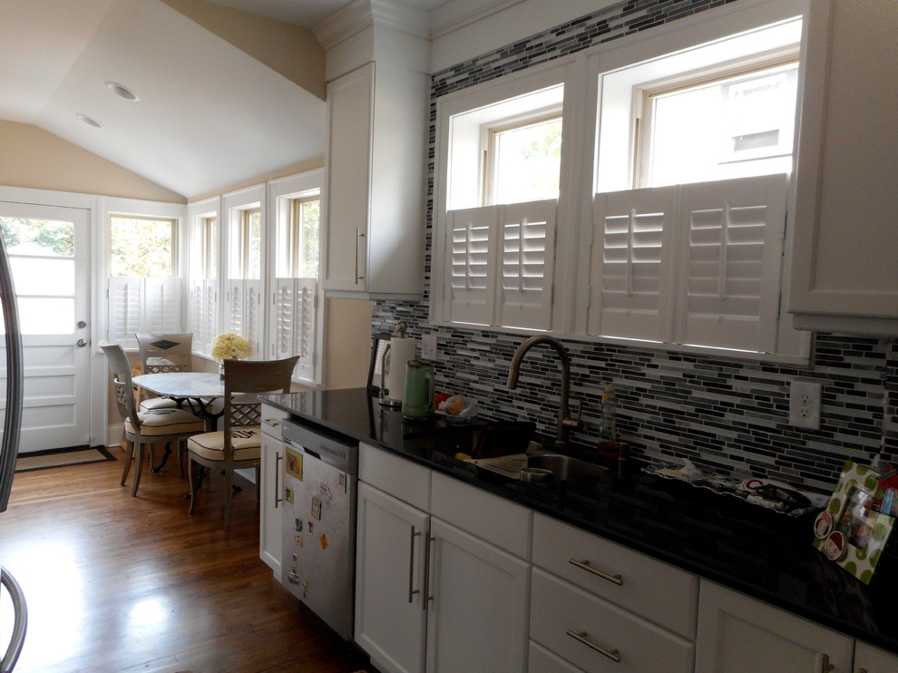 Mid-sized minimalist galley medium tone wood floor eat-in kitchen photo with a single-bowl sink, shaker cabinets, white cabinets, granite countertops, multicolored backsplash, matchstick tile backsplash and stainless steel appliances