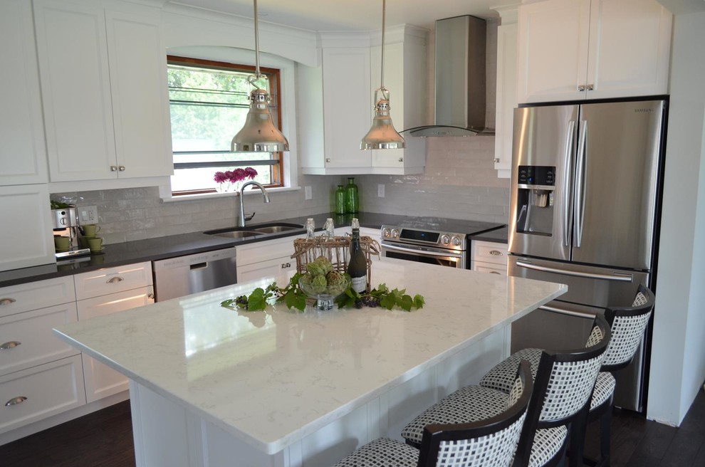 This is an example of a mid-sized transitional l-shaped open plan kitchen in Toronto with an undermount sink, recessed-panel cabinets, white cabinets, stainless steel appliances, dark hardwood floors, with island, quartz benchtops, grey splashback and ceramic splashback.