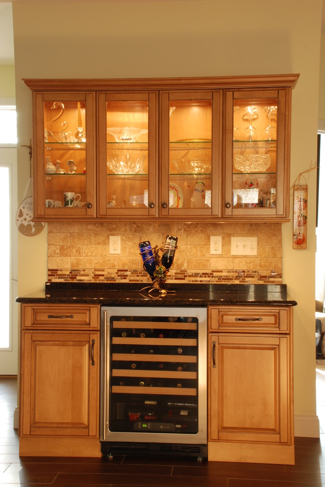 Mid-sized transitional l-shaped ceramic tile eat-in kitchen photo with a farmhouse sink, raised-panel cabinets, medium tone wood cabinets, granite countertops, beige backsplash, ceramic backsplash, stainless steel appliances and an island